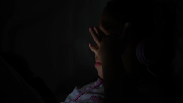 Night shoot: Little child playing smartphone lying on bed, light and the blue light has a negative effect on the child's eyes. Health care concept