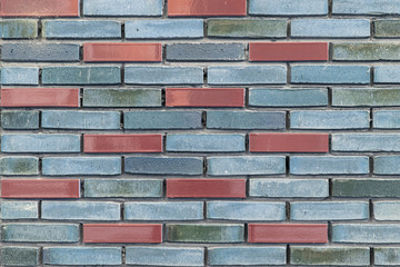 Blue and grey brick wall with a few brown colored bricks in it