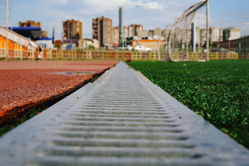 Fototapeta premium jogging track with metal grating and green grass.