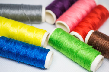Fototapeta na wymiar Multi-colored spools of cotton threads for sewing on a white background close-up