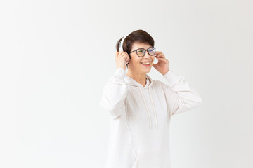 Beautiful woman 40-50 years old listening music in big headphone on white background with copy space