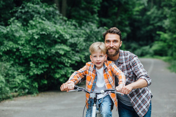 Happy smiling father with his son on a balance bike.