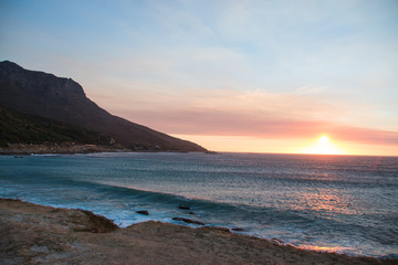 Fototapeta premium Chapman's Peak Drive Through the Mountains in Cape Town at Sunset Next to the Sea with Crashing Waves in South Africa