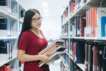 Portrait of young Asian woman with a book in library,Education Concept.