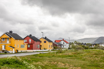 Fototapeta na wymiar Yellow, red and white norwegian houses along the road in Andenes village, Andoy Municipality, Vesteralen district, Nordland county, Norway