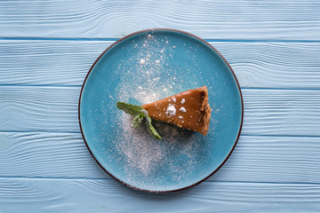 The cheesecake in a plate on a blue wooden table.
