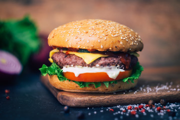 Home made Burger (cheeseburger) with beef on a wooden background. Classic home made Burger. Close up, copy space.