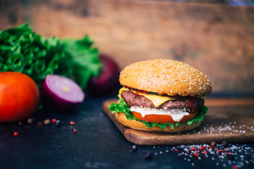 Home made Burger (cheeseburger) with beef on a wooden background. Classic home made Burger. Close up, copy space.