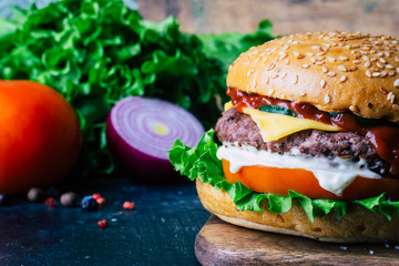 Home made Burger (cheeseburger) with beef on a wooden background. Classic home made Burger. Close up, copy space.