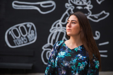 Portrait of the beautiful young brunette woman who is looking aside outdoors