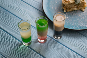 The cocktails and napoleon cake on a blue wooden table.