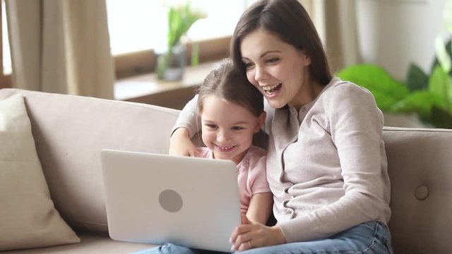 Happy mother with kid daughter making video call on laptop