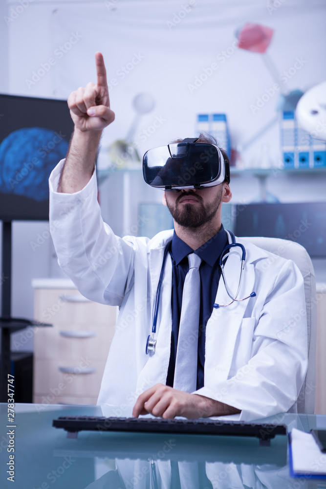 Wall mural young male doctor with virtual reality headset pointing