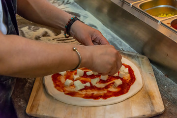 Adding cheese to a margherita pizza