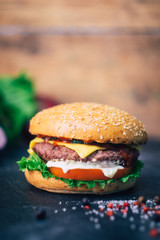 Home made Burger (cheeseburger) with beef on a wooden background. Classic home made Burger. Close up, copy space.