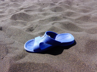 Flip flop on black sand