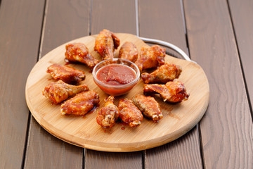 Spicy deep fried chicken wings and legs with dipping sauce on wooden plate , wood background.