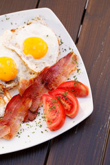 Healthy bacon fried egg on toast bread breakfast on plate , fresh tomatoes and cheese on plate , wood background.