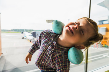 Close-up the happy little boy who is standing in the airport near the window
