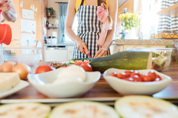 Woman putting vegetables in a bowl to make salad