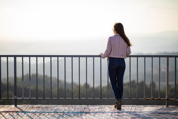 Beautiful woman back shot on a viewpoint railing with blurred background