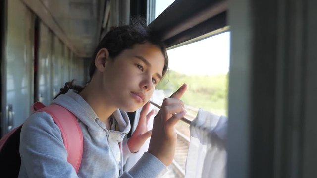 sad girl looks out the train window. travel transportation railroad concept. teen girl misses traveling in a train compartment looking out the window. long lifestyle train journey by rail