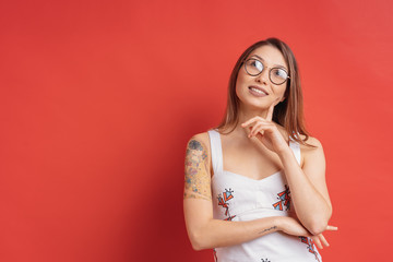 Caucasian woman with glasses thinking and imagination isolated on red background