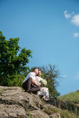 bride and groom sit on the stone, bottom view