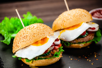 Tasty burgers with chips served on cutting board