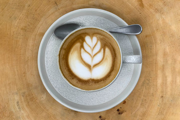 Cappuccino in a porcelain cup on a wooden board.