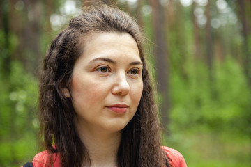 Young attractive woman looking to the right portrait in spring forest among trees
