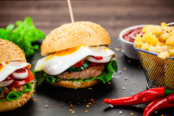 Tasty burgers with chips served on cutting board