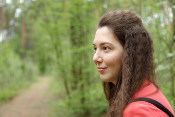 Young attractive woman looking to the left portrait in spring forest among trees