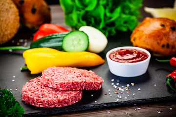 Fresh raw steaks on cutting board with vegetables