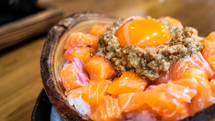 Japanese food, salmon sashimi, salmon donburi over rice bowl with fresh egg in the restaurant (Selective focus)