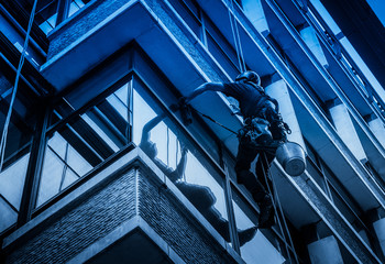 Obraz premium Window cleaner on the modern building performing his job. Limited colours.