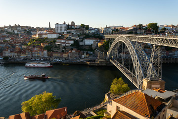 Fototapeta na wymiar View to the old city of Porto with the D. Luis bridge and colorful buildings. Warm golden light