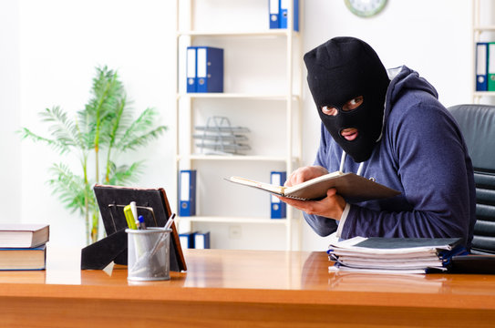 Male thief in balaclava in the office 