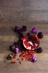 Ripe pomegranate fruit on wooden vintage background with roses