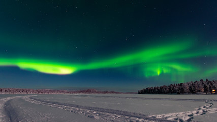 Finland, Helsinki - Jan 2019: View across the lake toward a forest as the northern light rise in to the sky as a vivid green band