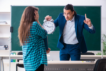 Young handsome teacher and female student in the classroom 