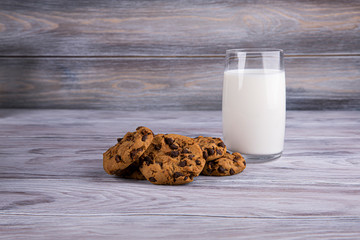 A stack of chocolate chip cookies lies near a glass of milk. Calcium-rich milk.