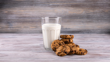 A stack of chocolate chip cookies lies near a glass of milk. Calcium-rich milk.