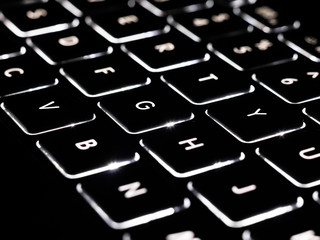 Black and white close-up on illuminated keys of computer keyboard.
