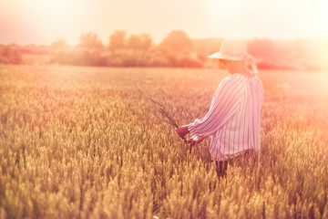 Woman holds ear of wheat in hand, woman in wheat field