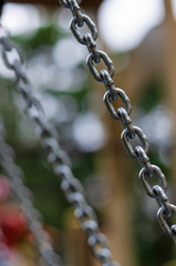 Diagonal chain with oval links on the background bokeh with blurred chains