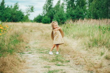 Fototapeta na wymiar Cute happy little baby girl play with big hat outdoors.