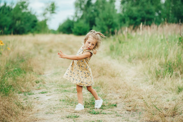 Joyful little girl having fun on the green grass in hands in nature.
