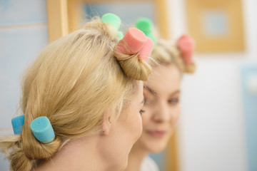 Fototapeta premium Blonde woman using hair rollers
