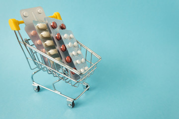 Shopping for medicines, healthcare costs and prescription medication concept with shopping cart or...
